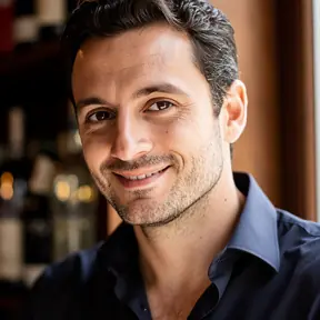 Close-up portrait of a French man in his late 30s, approachable expression, natural soft light, blurred background hinting at a wine bar, editorial lifestyle photography, realistic, high resolution
